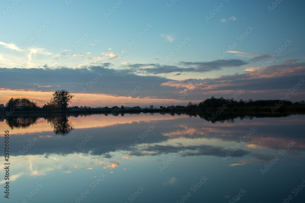 Evening at the lake and reflection of clouds after sunset in the water