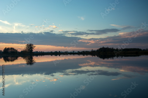 Evening at the lake and reflection of clouds after sunset in the water