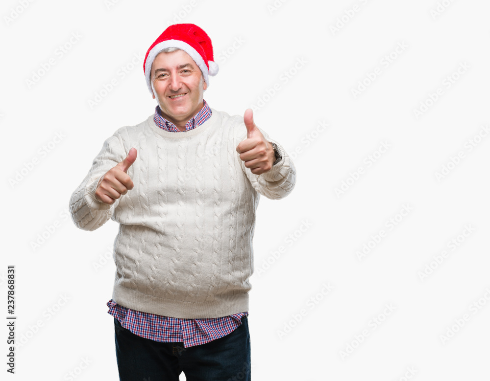 Handsome senior man wearing christmas hat over isolated background approving doing positive gesture with hand, thumbs up smiling and happy for success. Looking at the camera, winner gesture.
