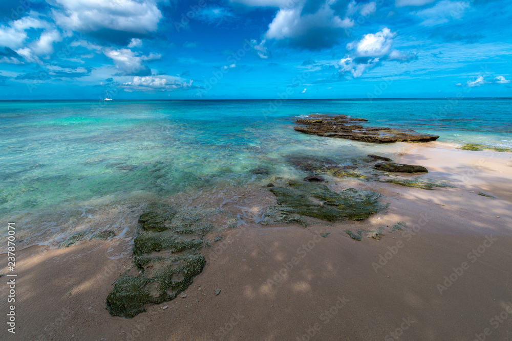 Karibik pur, Sand und Felsen vor blaugrüner Wasserkulisse