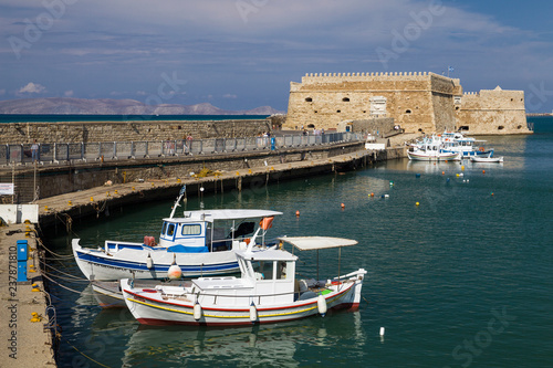 Fishing Boats under the walls of Koules Fortress in Heraklion. Fortress on the sea, tourist attraction of the city of Heraklion. Historic building in Crete, Greece.