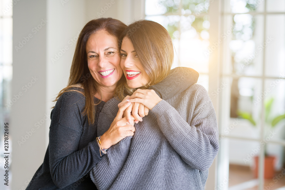 Beautiful family of mother and daughter together, hugging and kissing at home - obrazy, fototapety, plakaty 