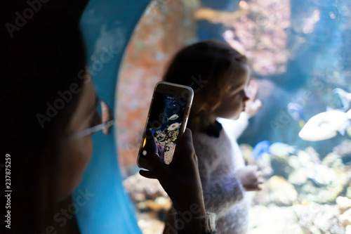 Young woman with child watch a fish in aquarium