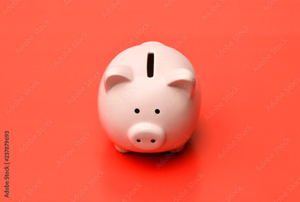 Pink piggy Bank stands in the center on a red background with a shadow. Horizontal photography Pink piggy Bank stands in the center on a red background with a shadow. Horizontal photography
