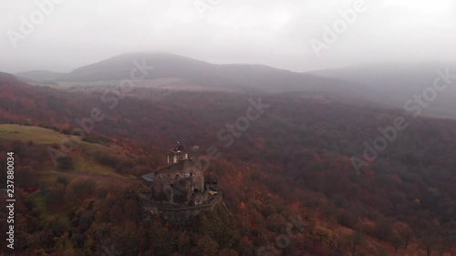 Aerial parallax shot flying over the historic and beautiful Holloko Castle in Hungary on a foggy and colourful Autumn day photo