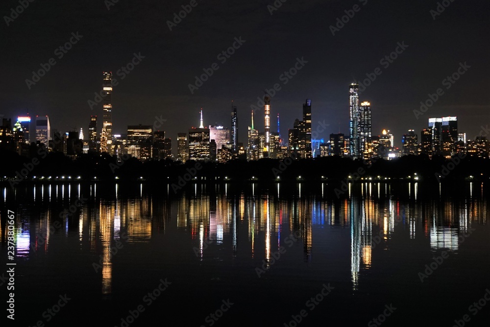 Naklejka premium Lights of the Manhattan Skyline Reflecting in a Lake in Central Park. New York, USA