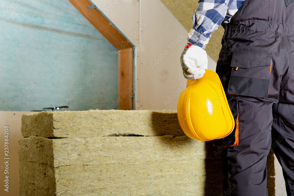 Man installing thermal roof insulation layer - using mineral wool panels. Attic renovation and insulation concept Man installing thermal roof insulation layer - using mineral wool panels. Attic renovation and insulation concept