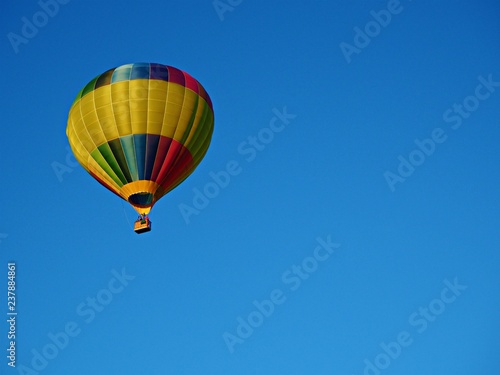 Brightly coloured hot air balloon in a clear blue sky with copy space