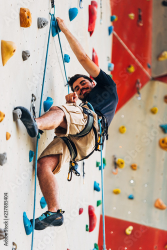 Sporty young man training in a colorful climbing gym