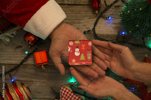 Fotografi Santa Claus offering a small gift box to a happy woman on a festive Christmas de