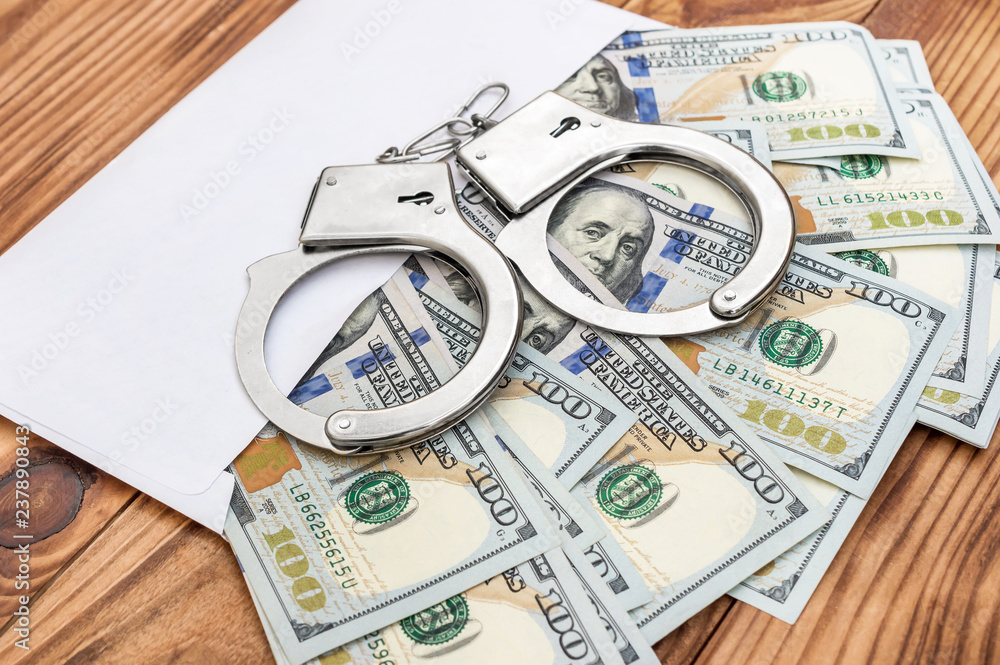Envelope with money and handcuffs on the table. Envelope with money and handcuffs on the table.