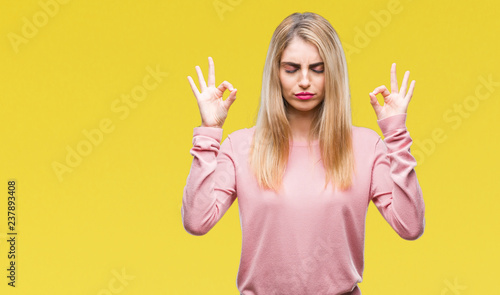 Young beautiful blonde woman wearing pink winter sweater over isolated background relax and smiling with eyes closed doing meditation gesture with fingers. Yoga concept.