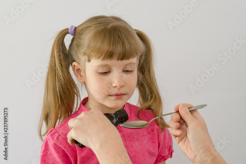 child kid poured syrup medicine in a spoon