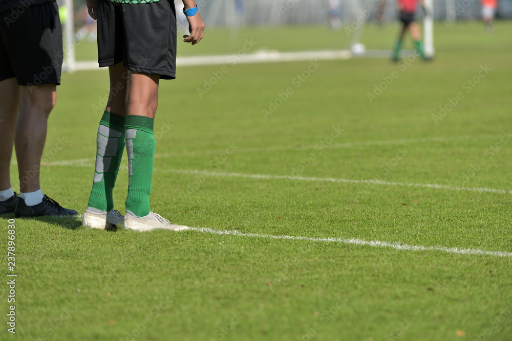 A substitution football player waiting on the side line with his coach while watching his teammate in a Boys' Under 18 years school soccer tournament. A substitution football player waiting on the side line with his coach while watching his teammate in a Boys' Under 18 years school soccer tournament.