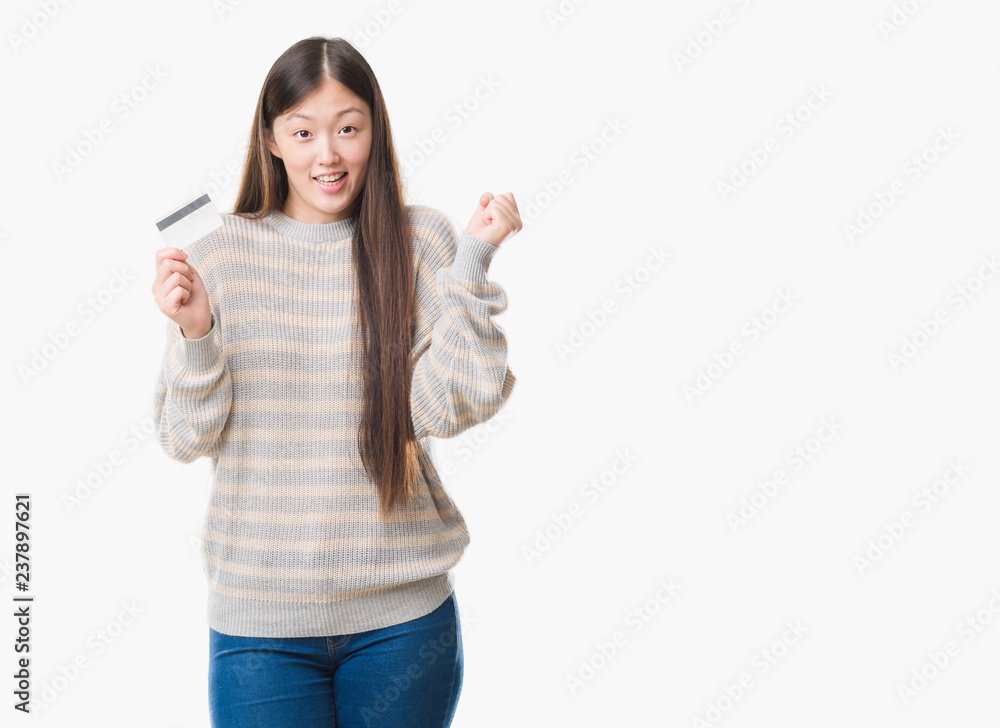 Young Chinese woman over isolated background holding credit card screaming proud and celebrating victory and success very excited, cheering emotion Young Chinese woman over isolated background holding credit card screaming proud and celebrating victory and success very excited, cheering emotion
