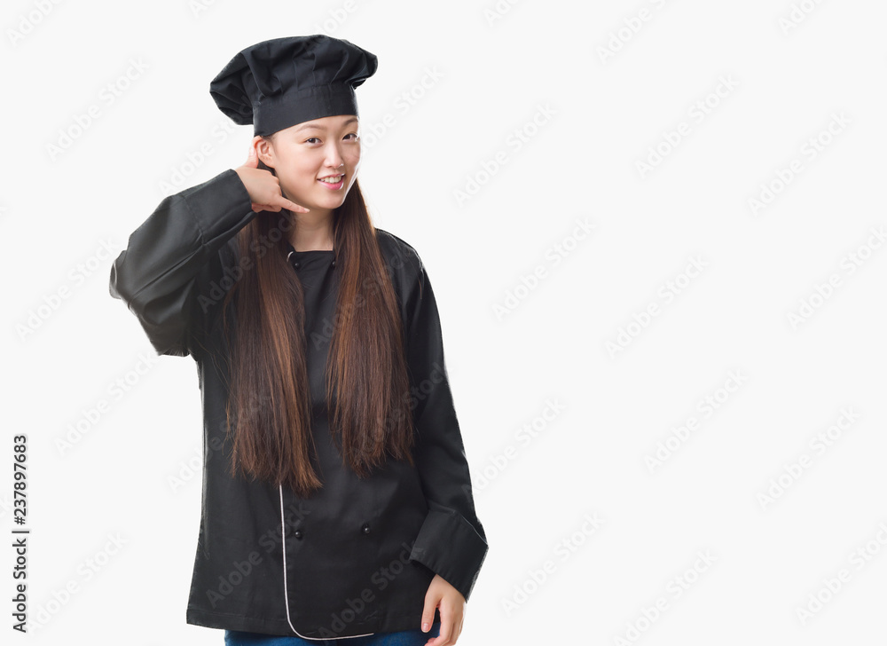 Young Chinese woman over isolated background wearing chef uniform smiling doing phone gesture with hand and fingers like talking on the telephone. Communicating concepts. Young Chinese woman over isolated background wearing chef uniform smiling doing phone gesture with hand and fingers like talking on the telephone. Communicating concepts.