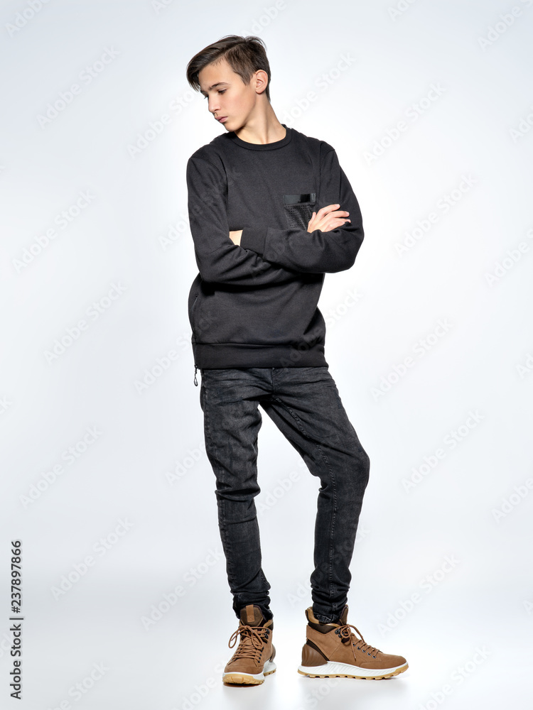 Teenage boy dressed in black trendy clothes posing at studio. Teenage boy dressed in black trendy clothes posing at studio.