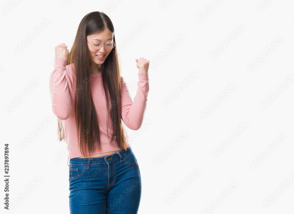 Young Chinese woman over isolated background wearing glasses very happy and excited doing winner gesture with arms raised, smiling and screaming for success. Celebration concept. Young Chinese woman over isolated background wearing glasses very happy and excited doing winner gesture with arms raised, smiling and screaming for success. Celebration concept.