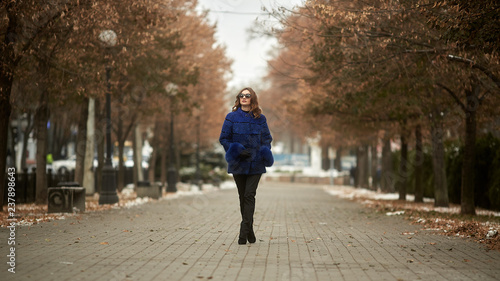 The girl walks through the city in a fur coat