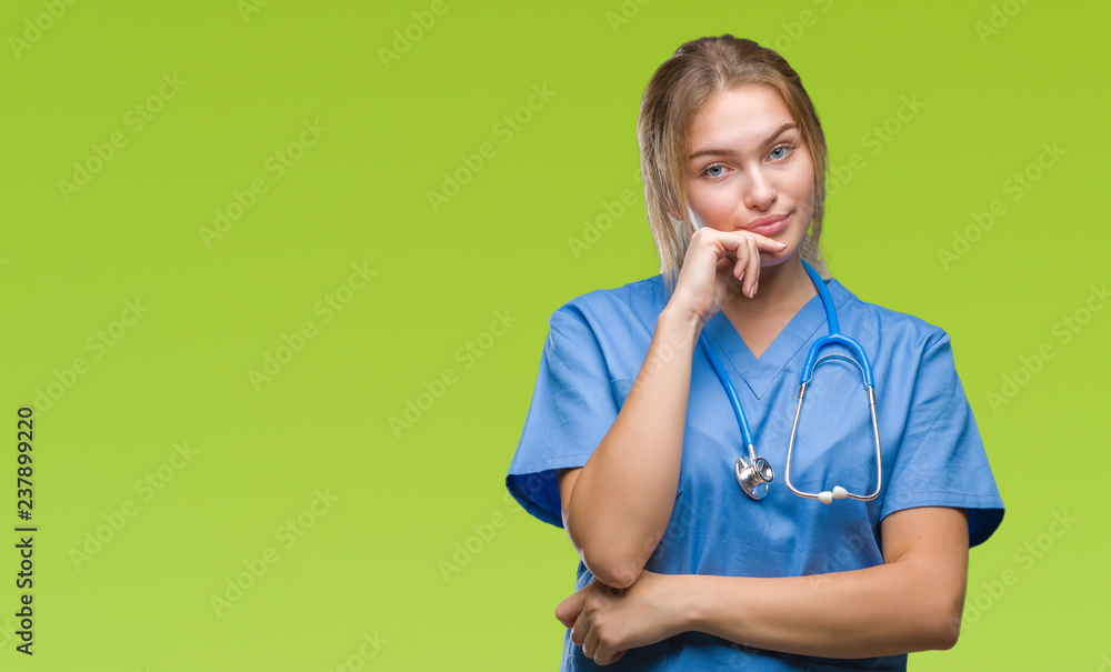 Young caucasian doctor woman wearing surgeon uniform over isolated background looking confident at the camera with smile with crossed arms and hand raised on chin. Thinking positive. Young caucasian doctor woman wearing surgeon uniform over isolated background looking confident at the camera with smile with crossed arms and hand raised on chin. Thinking positive.