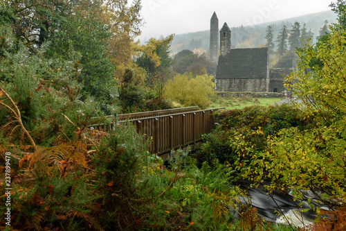 A wooden bridge, medieval church and round tower during autumn