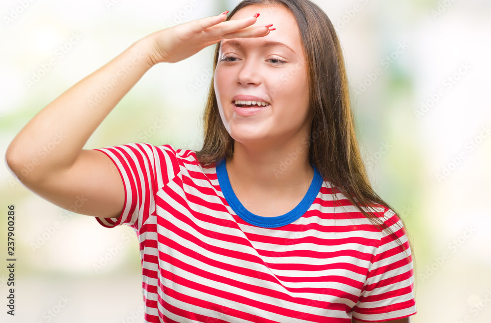 Young caucasian beautiful woman over isolated background very happy and smiling looking far away with hand over head. Searching concept. Young caucasian beautiful woman over isolated background very happy and smiling looking far away with hand over head. Searching concept.