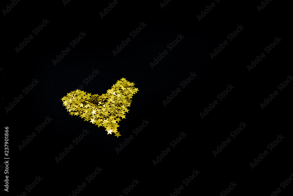 Golden stars confetti on dark black background. Holiday concept. Many objects, horizontal view, top view