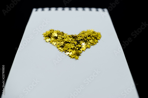 Spiral Notebook, realistic mockup White scetchbook on black abstract background with golden stars confetti.Horizontal top view.. photo