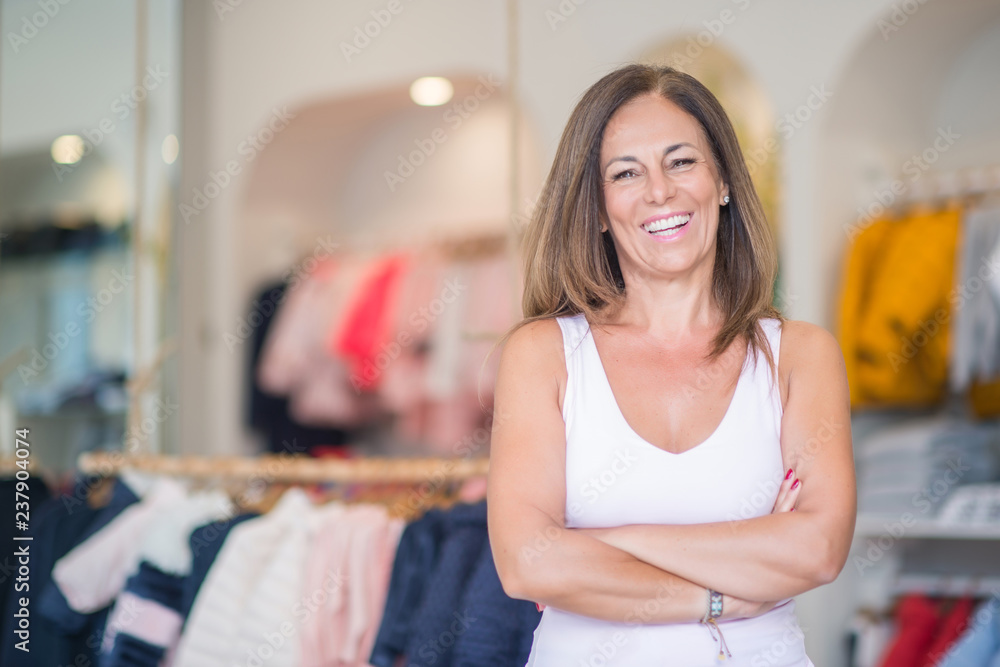 Beautiful middle age hispanic woman standing with smile on face at clothes store. Shop owner and shop assistant smiling confident and cheerful with crossed arms. Beautiful middle age hispanic woman standing with smile on face at clothes store. Shop owner and shop assistant smiling confident and cheerful with crossed arms.