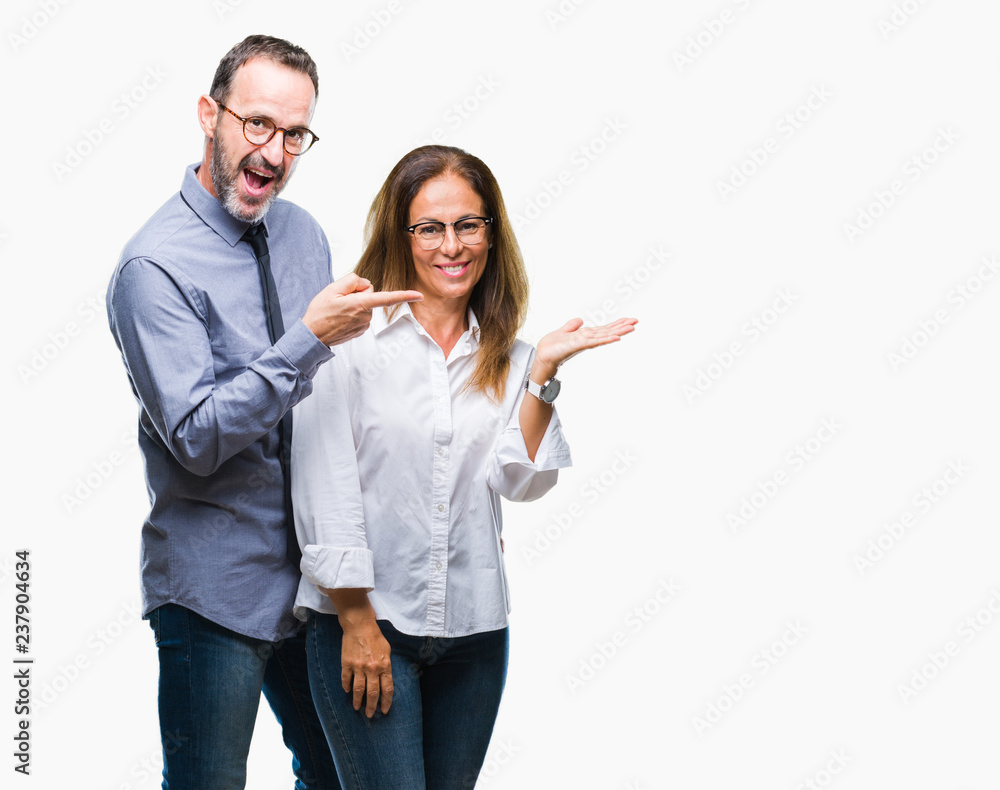 Middle age hispanic couple in love wearing glasses over isolated background amazed and smiling to the camera while presenting with hand and pointing with finger. Middle age hispanic couple in love wearing glasses over isolated background amazed and smiling to the camera while presenting with hand and pointing with finger.