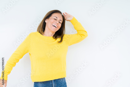 Beautiful middle age woman wearing yellow sweater over isolated background Dancing happy and cheerful  smiling moving casual and confident listening to music