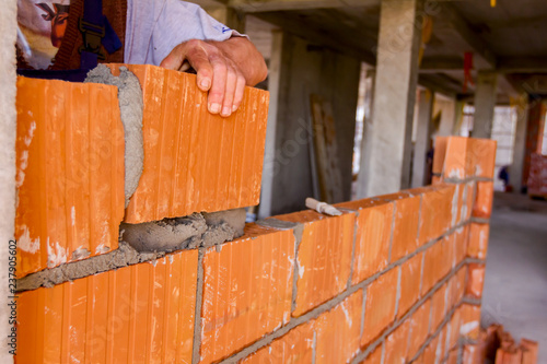 Worker is building wall with red blocks and mortar