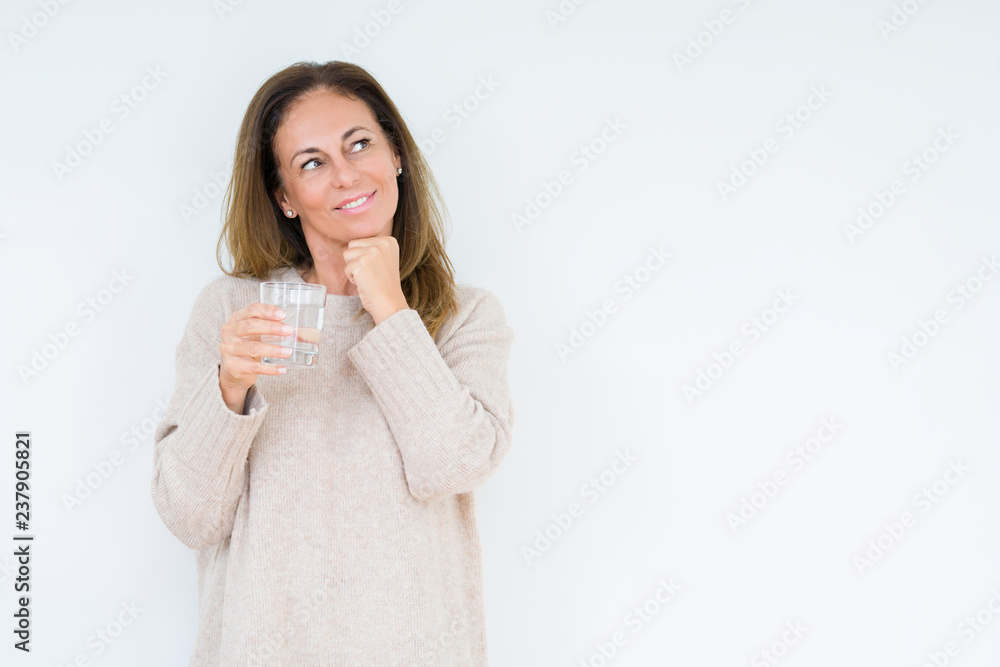 Middle age woman drinking glass of water isolated background serious face thinking about question, very confused idea Middle age woman drinking glass of water isolated background serious face thinking about question, very confused idea