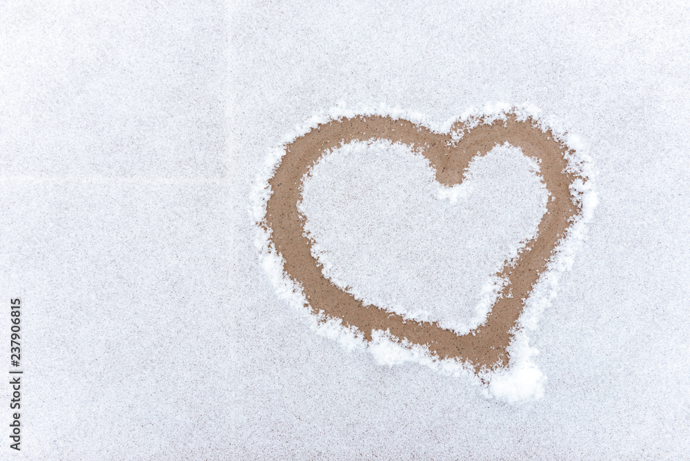 Drawing heart on white snow.