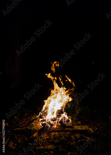 Fireplace with fire, firewoods and coal in the night, nature hiking photo