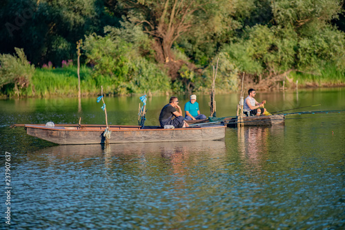 Novi Sad, Serbia - August 04, 2018: Danube island (Šodroš) near Novi Sad, Serbia. Fishermans sitting in boat and holding fishing rod.