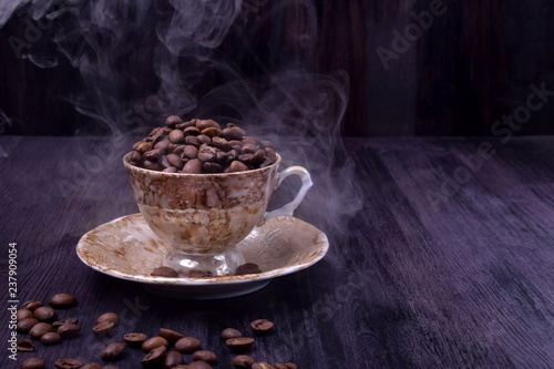 Freshly roasted coffee beans in a cup against the dark wooden background