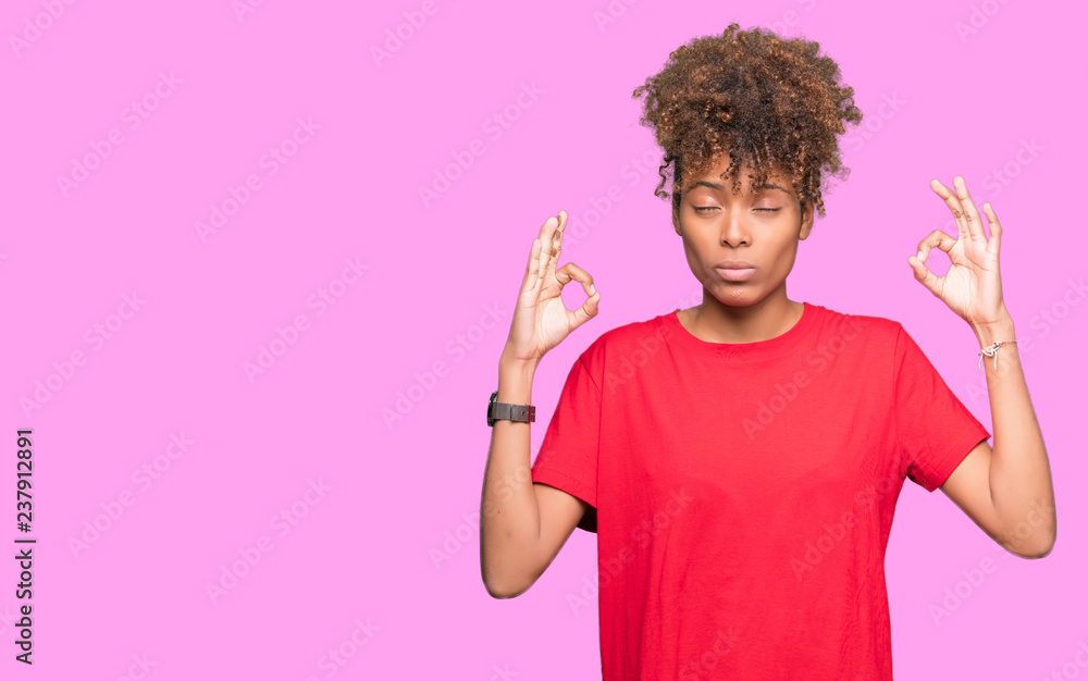 Beautiful young african american woman over isolated background relax and smiling with eyes closed doing meditation gesture with fingers. Yoga concept. Beautiful young african american woman over isolated background relax and smiling with eyes closed doing meditation gesture with fingers. Yoga concept.