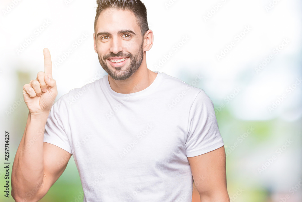 Young man wearing casual white t-shirt over isolated background pointing finger up with successful idea. Exited and happy. Number one. Young man wearing casual white t-shirt over isolated background pointing finger up with successful idea. Exited and happy. Number one.