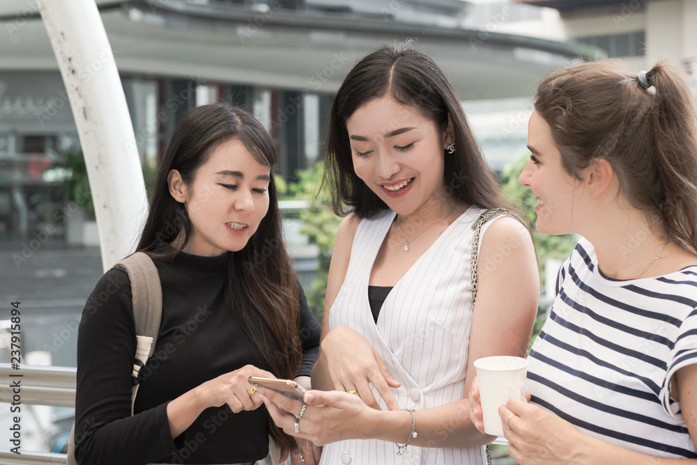 Girls looking at smartphone at the outdoor near sky train Girls looking at smartphone at the outdoor near sky train