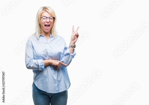 Young beautiful blonde business woman wearing glasses over isolated background smiling with happy face winking at the camera doing victory sign. Number two.