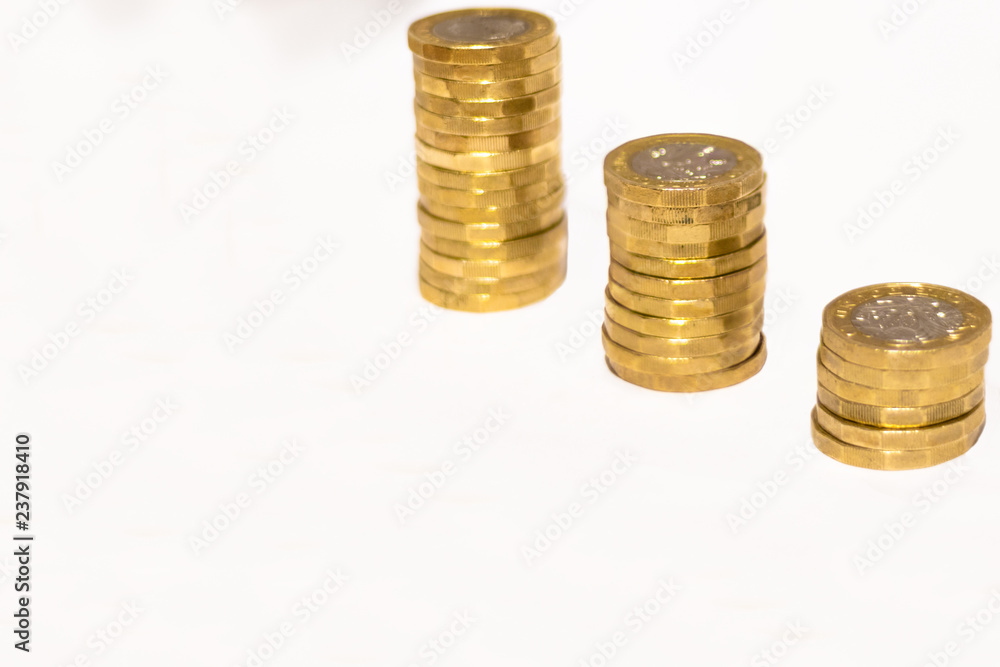 Stacks and Heaps of British GBP Golden Coins Currency Money on white background with empty space Stacks and Heaps of British GBP Golden Coins Currency Money on white background with empty space