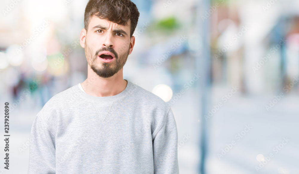 Young handsome man wearing sweatshirt over isolated background In shock face, looking skeptical and sarcastic, surprised with open mouth Young handsome man wearing sweatshirt over isolated background In shock face, looking skeptical and sarcastic, surprised with open mouth