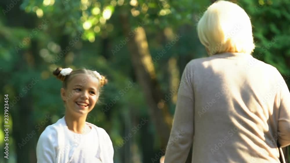 Little active girl emotionally talking to granny while walking in park, family Little active girl emotionally talking to granny while walking in park, family