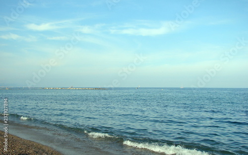 The pre-dawn landscape of the Spanish coast of the Mediterranean Sea against the background of a cloudy blue sky on the horizon.