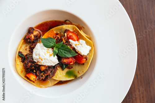 Ravioli with ricotta cheese and tomato served in white plate.