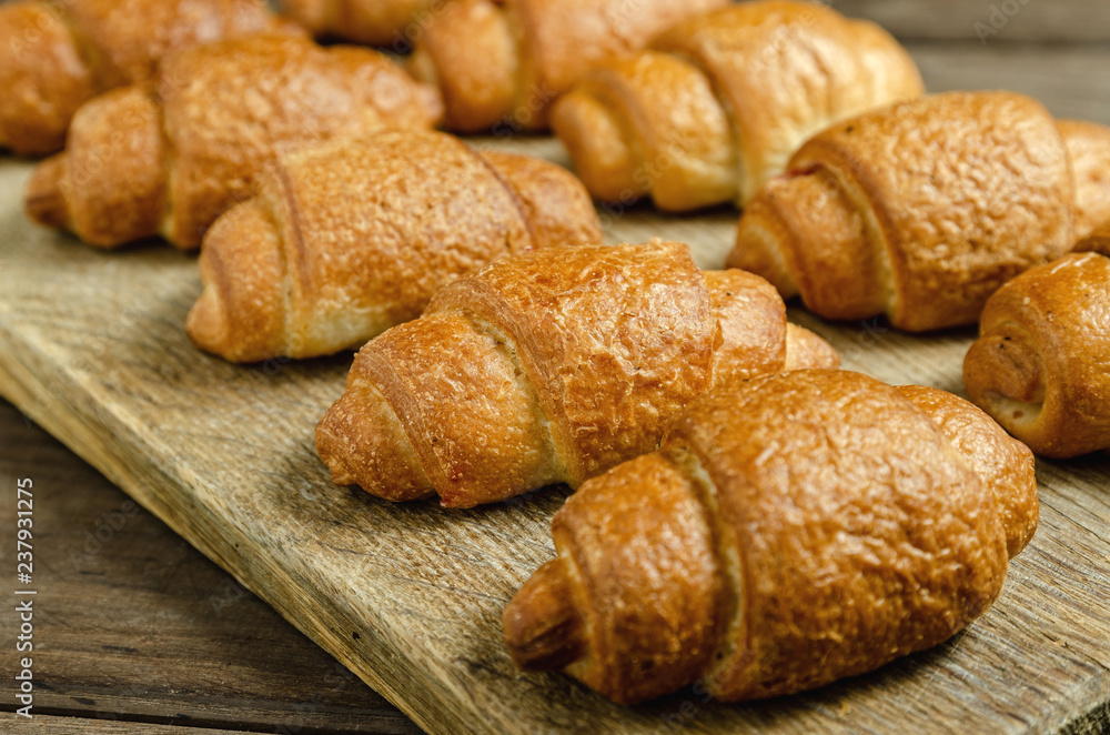 Fresh baked croissants on a wooden stand. Fresh baked croissants on a wooden stand.