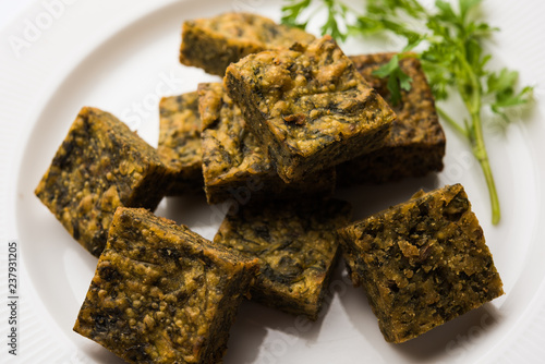 A savory cilantro cake or kothimbir vadi in square shape which is first steamed and then fried until crisp. popular indian snack served with hot tea and tomato ketchup photo