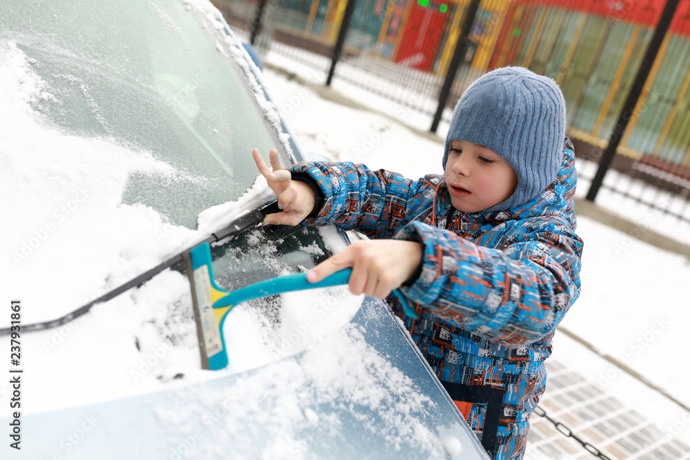 Boy scraping snow from car Boy scraping snow from car