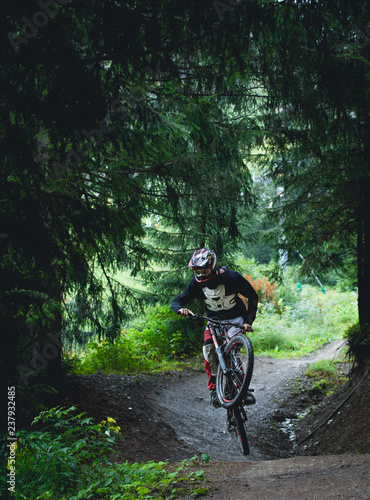 Downhill mountain bike rider jumping in forest